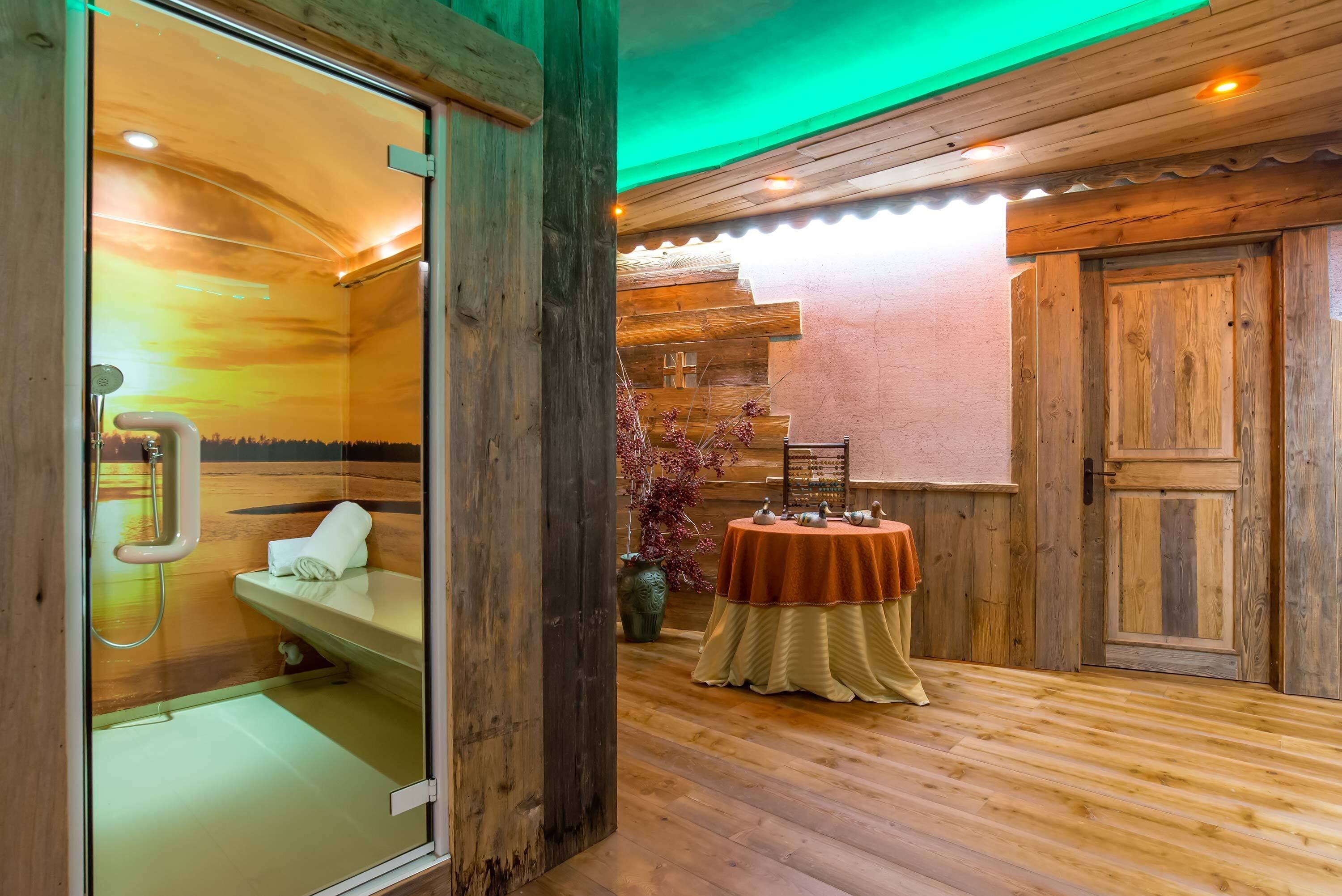 Un intérieur en bois avec une baignoire en bois, une table avec des théières et une porte en bois.