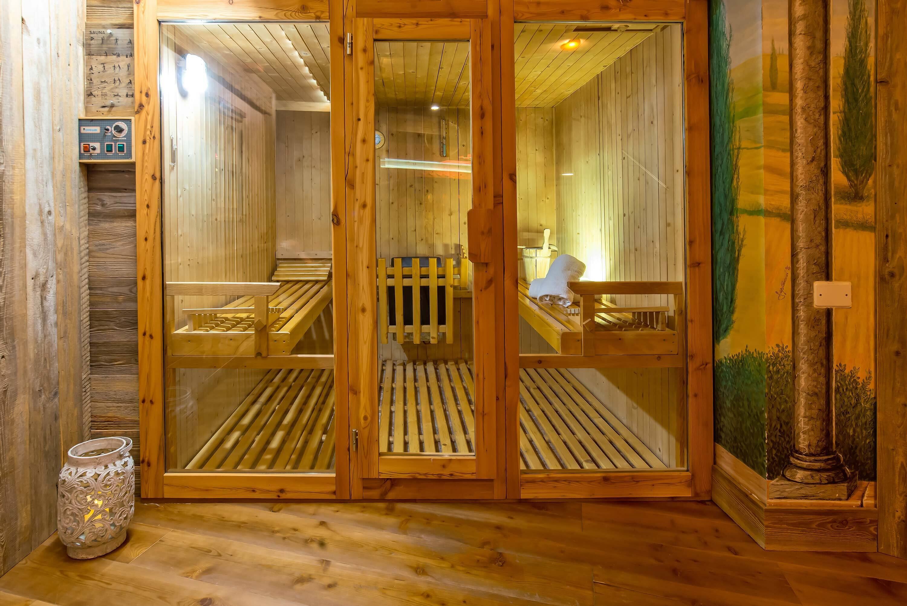 A sauna room with wooden benches, a control panel, and a decorative vase.