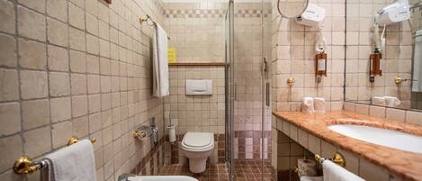 Un baño con lavamanos, bidé, inodoro y cabina de ducha de vidrio.