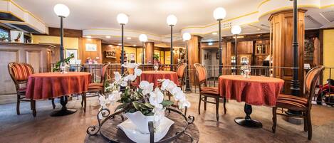 Un hall d’hôtel avec des tables rondes, des chaises et un élément décoratif central.