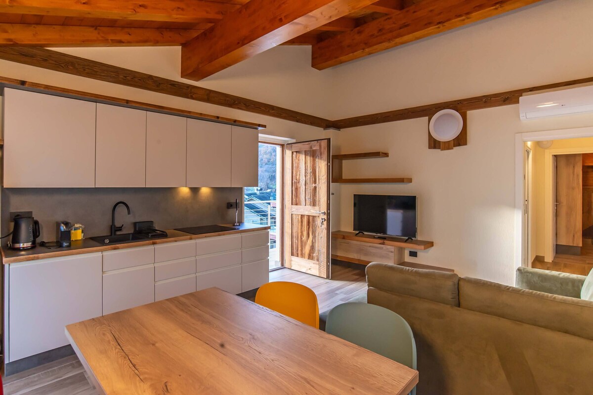 Una cocina moderna con armarios blancos, una mesa de comedor de madera y un televisor.