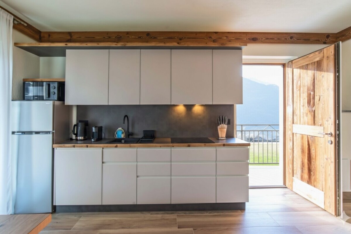 Una cocina moderna con armarios blancos, encimera de madera y vistas al exterior.