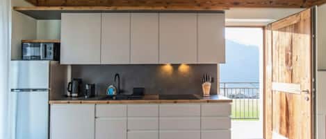 Una cocina moderna con armarios blancos, encimera de madera y vistas al exterior.