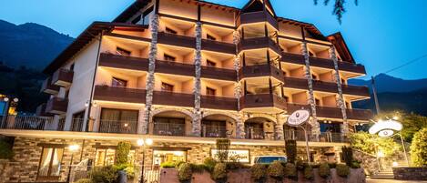 Un hotel de varios pisos con balcones, fachada de piedra y un cartel que indica que es un hotel.