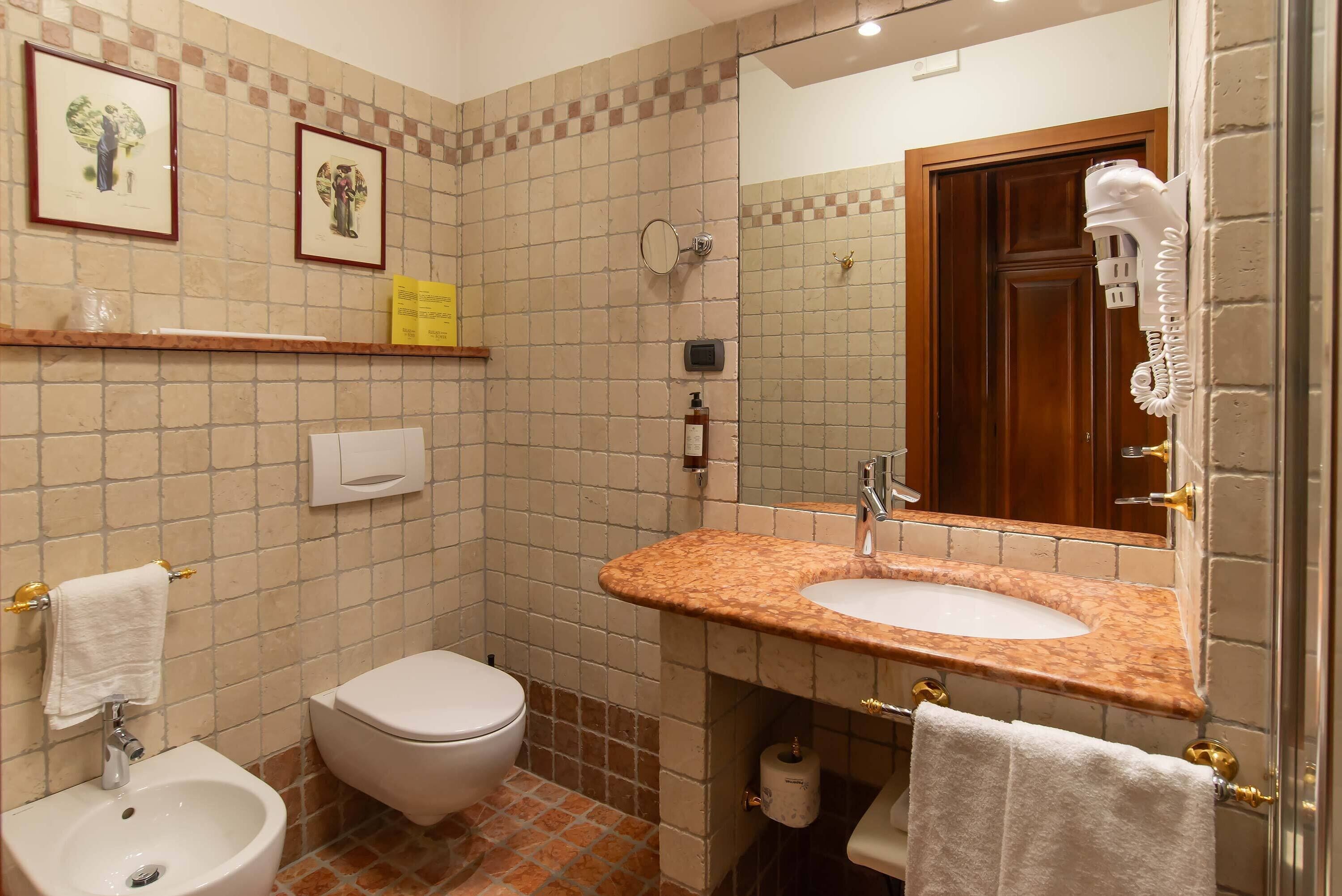 Une salle de bain équipée d’un lavabo, de toilettes, d’un bidet et d’un miroir.