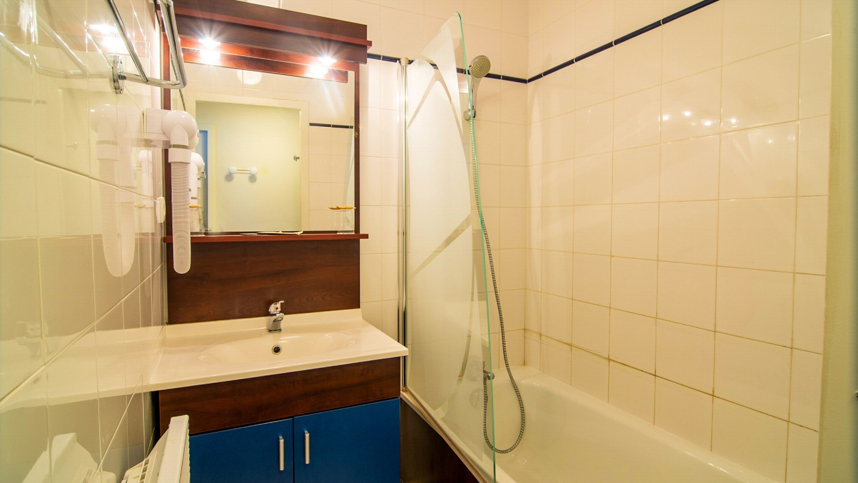 Un baño con una bañera blanca, un armario azul, un espejo y una ducha.