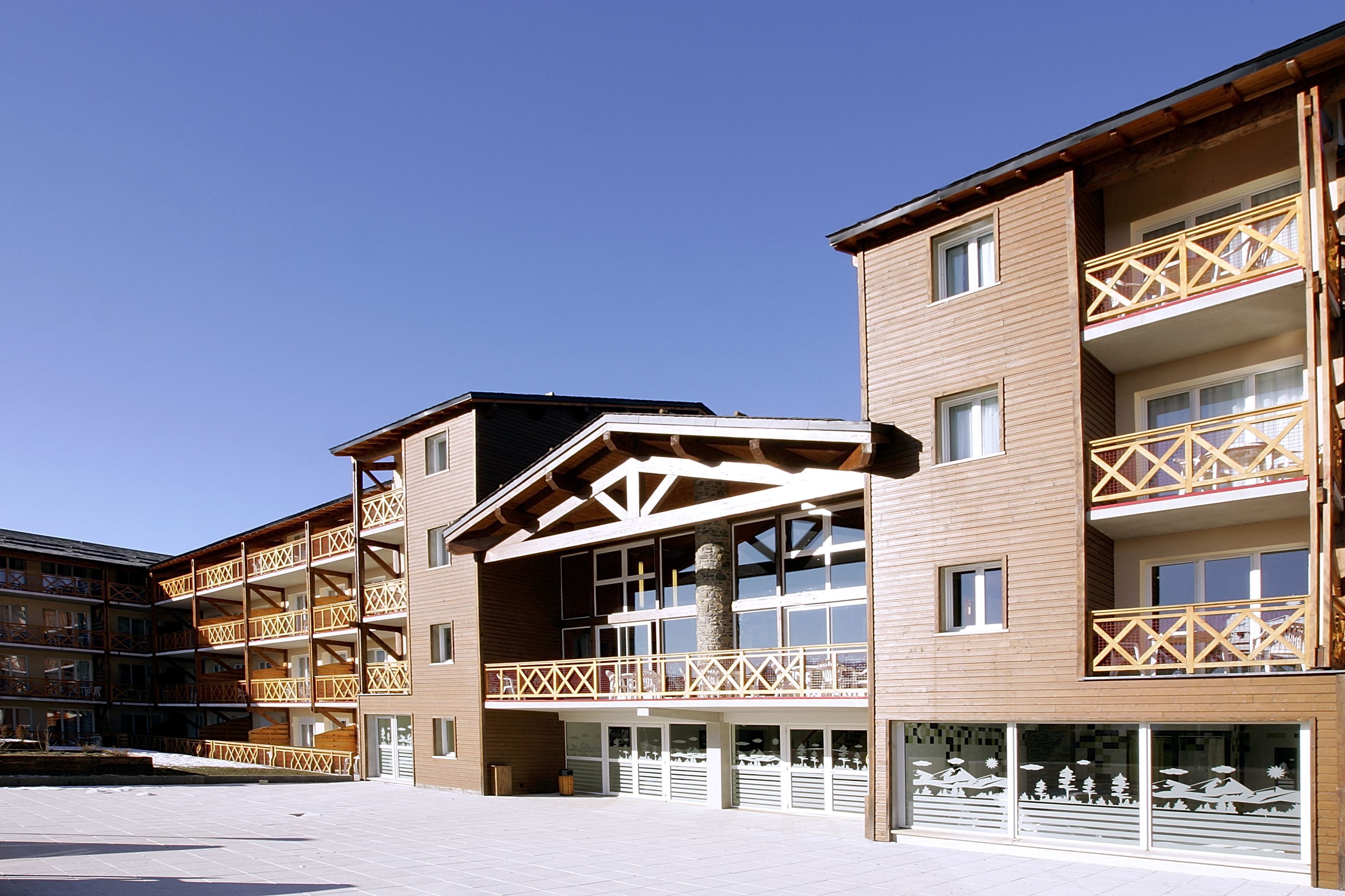 A multi-story hotel with balconies, large windows, and a covered outdoor area.