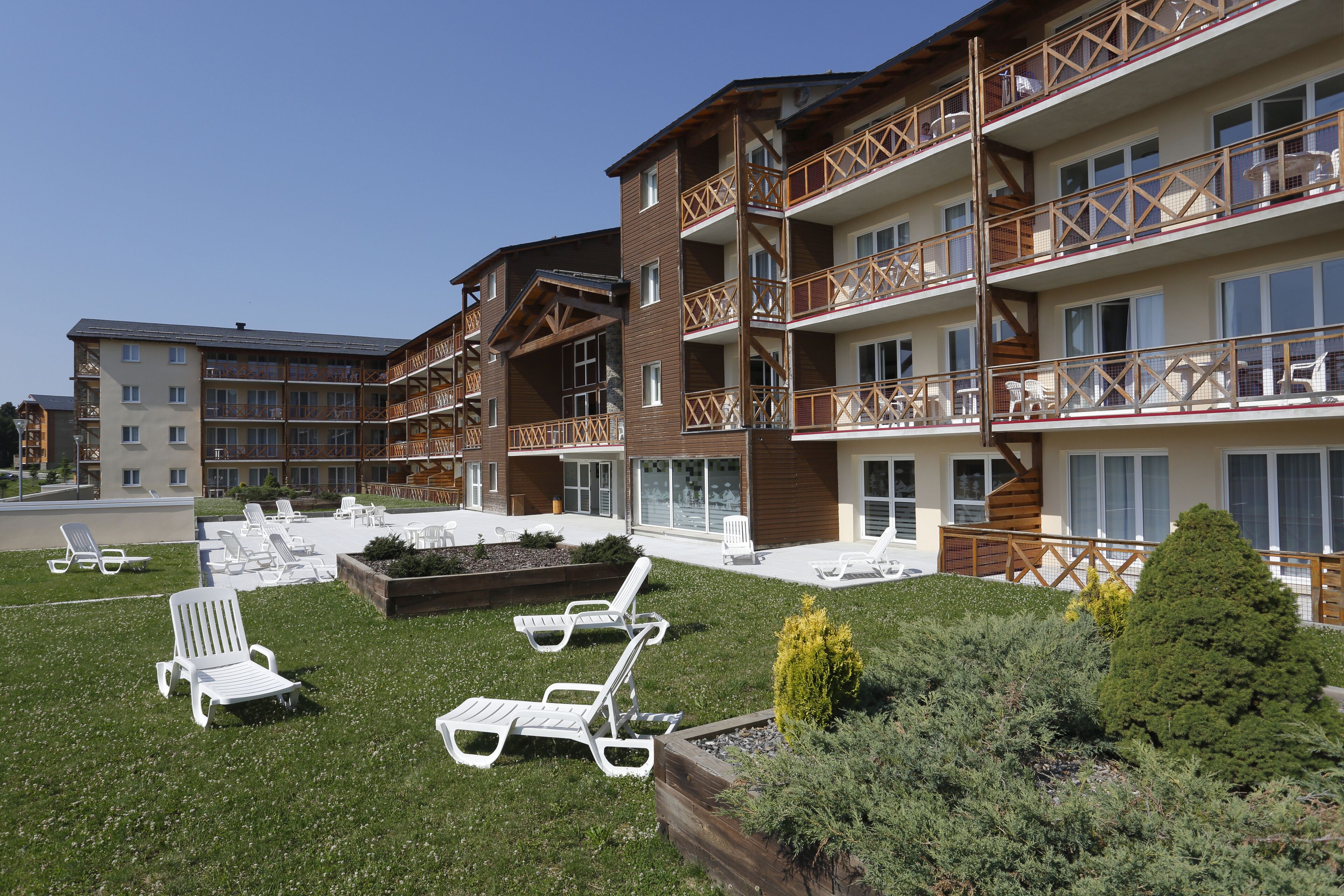 A multi-story hotel with outdoor seating and a well-maintained lawn.