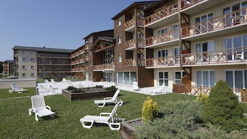A multi-story hotel with outdoor seating and a well-maintained lawn.
