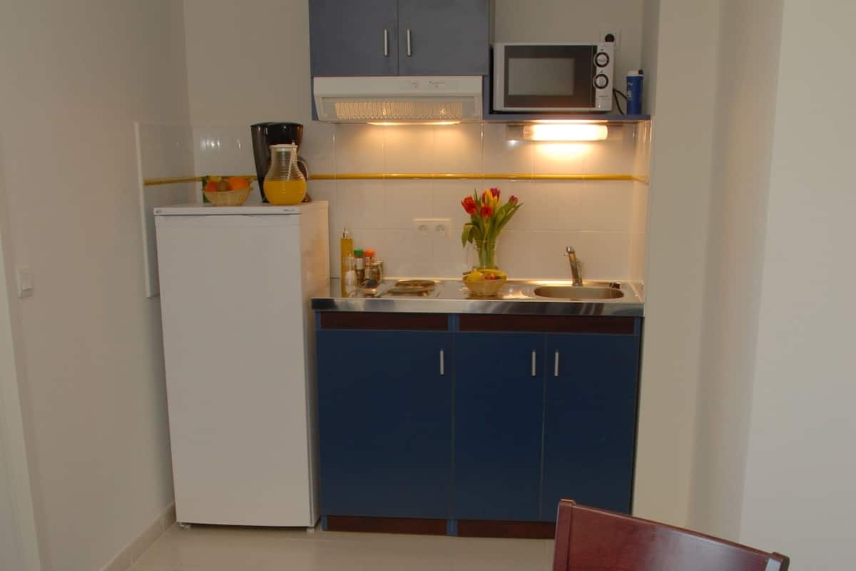 A breakfast setup with a table, breakfast items, and a kitchen in the background.