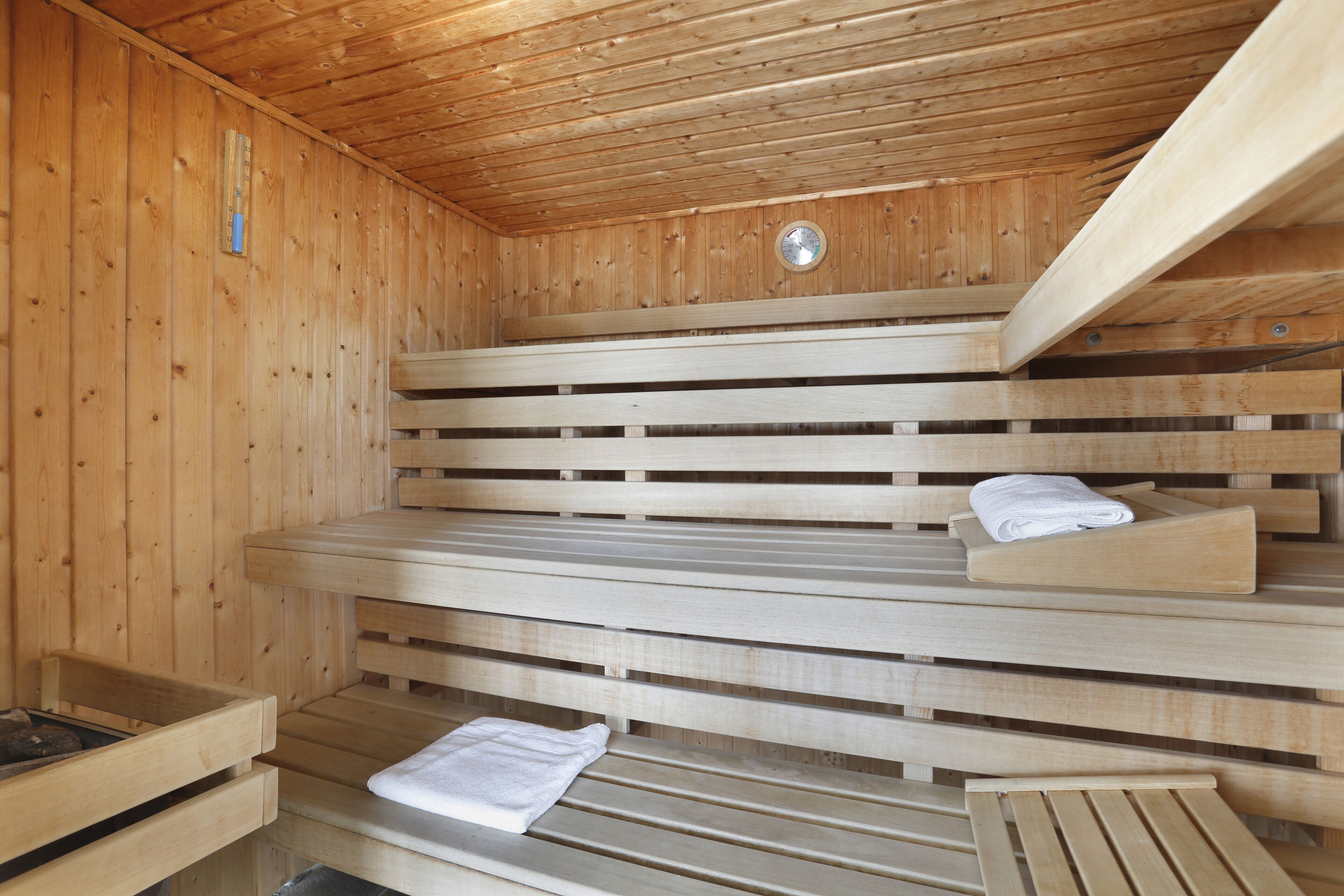 Uma sauna de madeira com bancos e um banco com toalha.