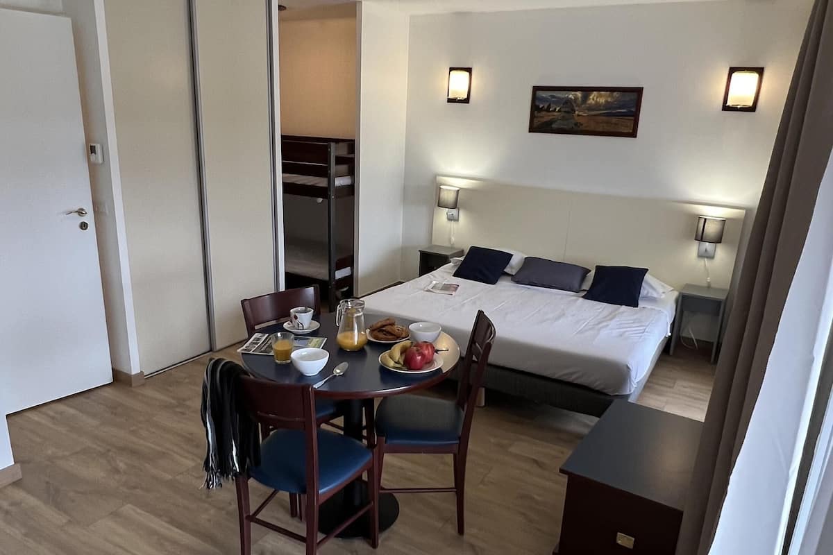 A hotel room with a bed, a dining table with breakfast items, and a closet.