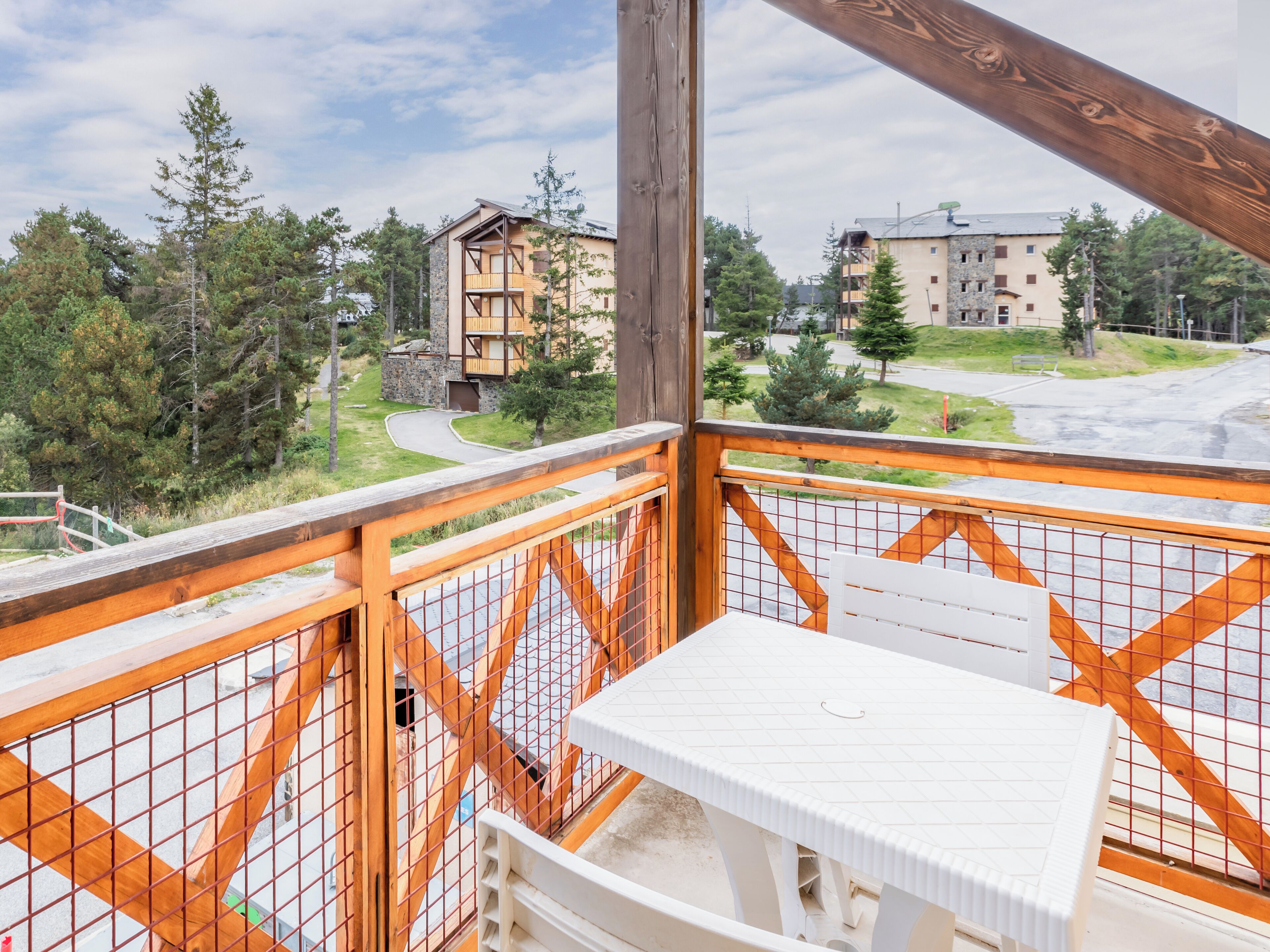 A balcony with a view of a residential area, including a building with a stone facade and a wooden deck.
