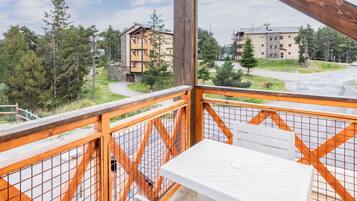 A balcony with a view of a residential area, including a building with a stone facade and a wooden deck.