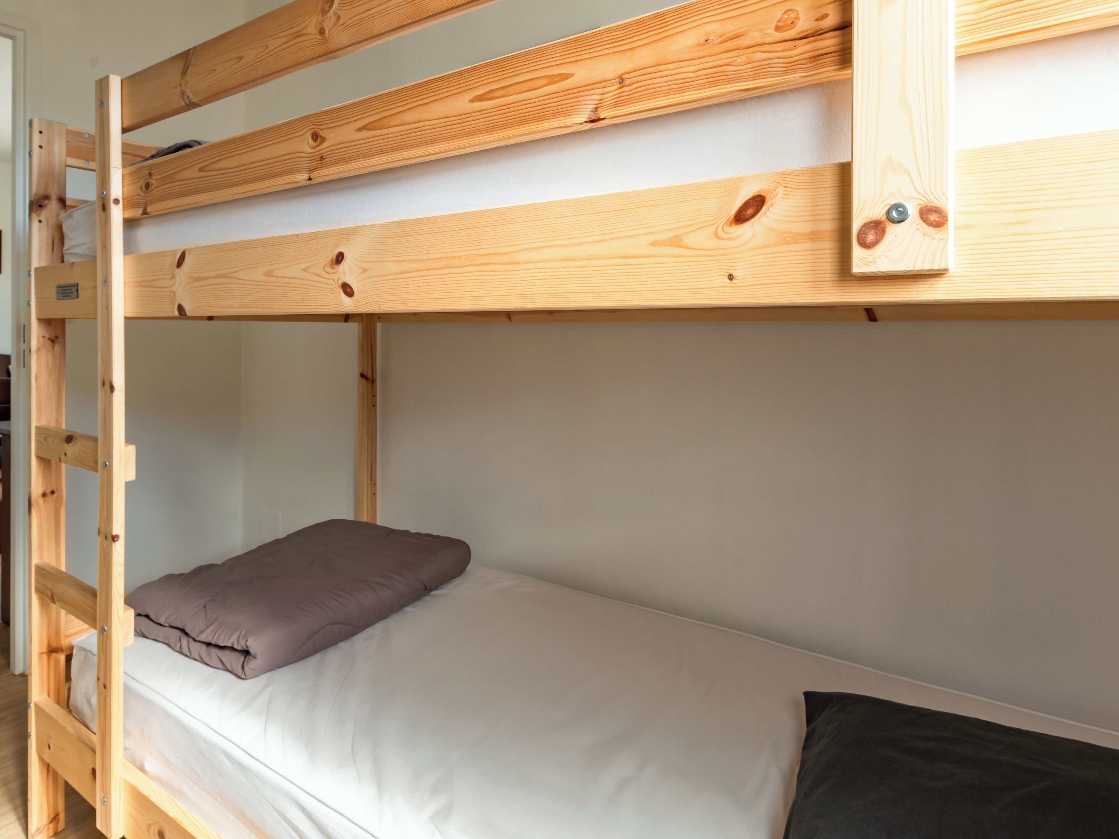 A bunk bed with a wooden frame, a mattress, and pillows.