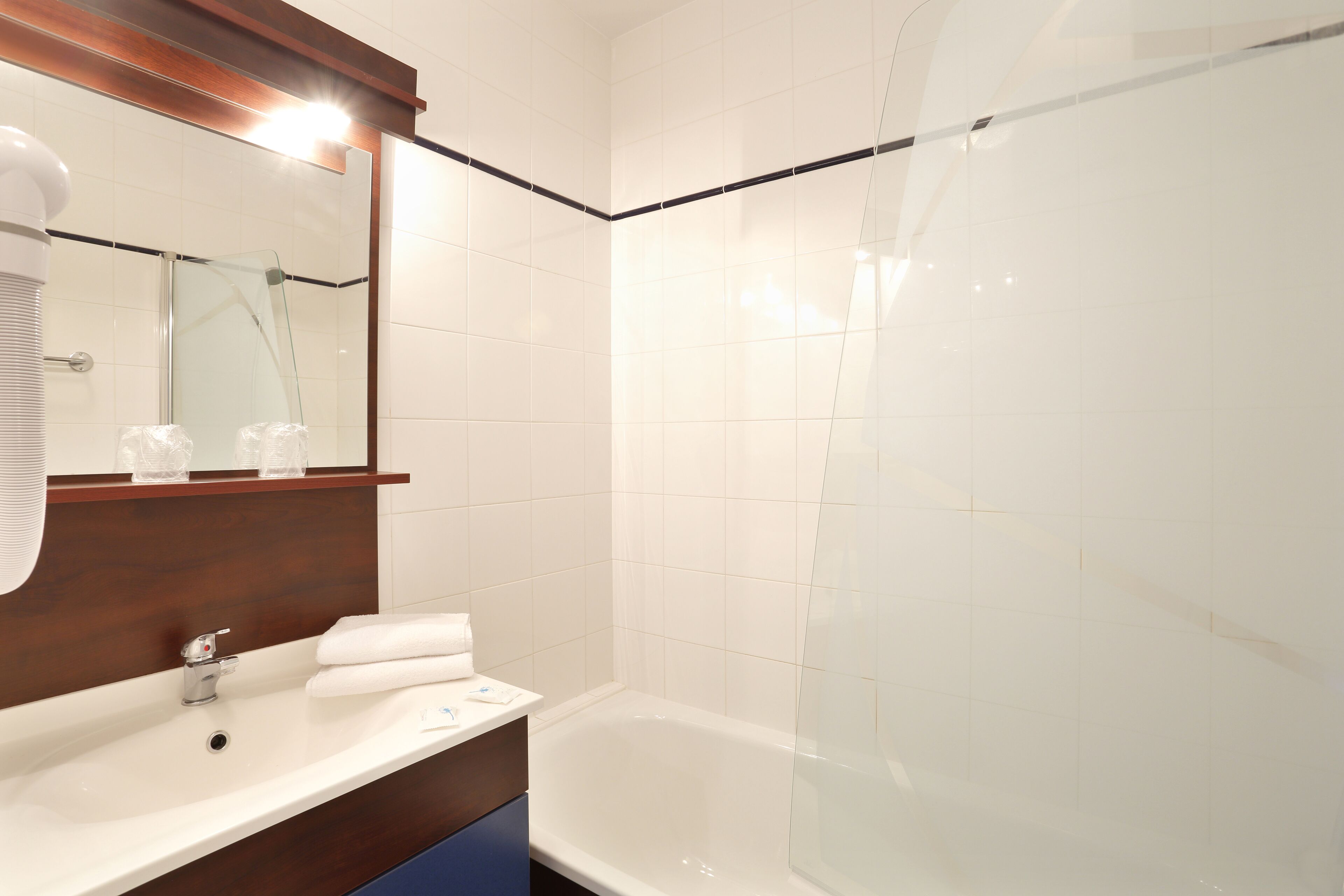 A bathroom with a white sink, mirror, and bathtub.
