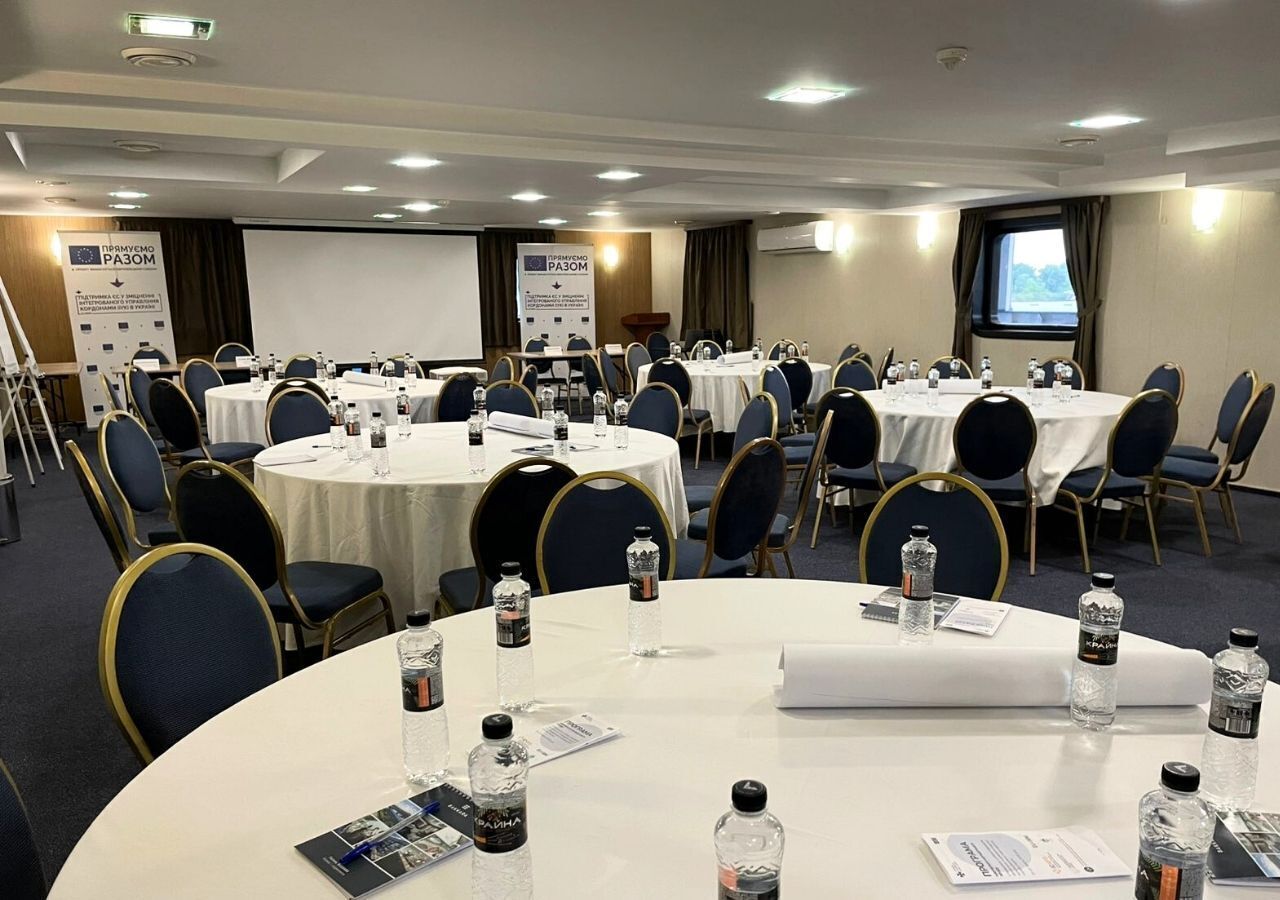 A conference room with round tables, chairs, and water bottles.