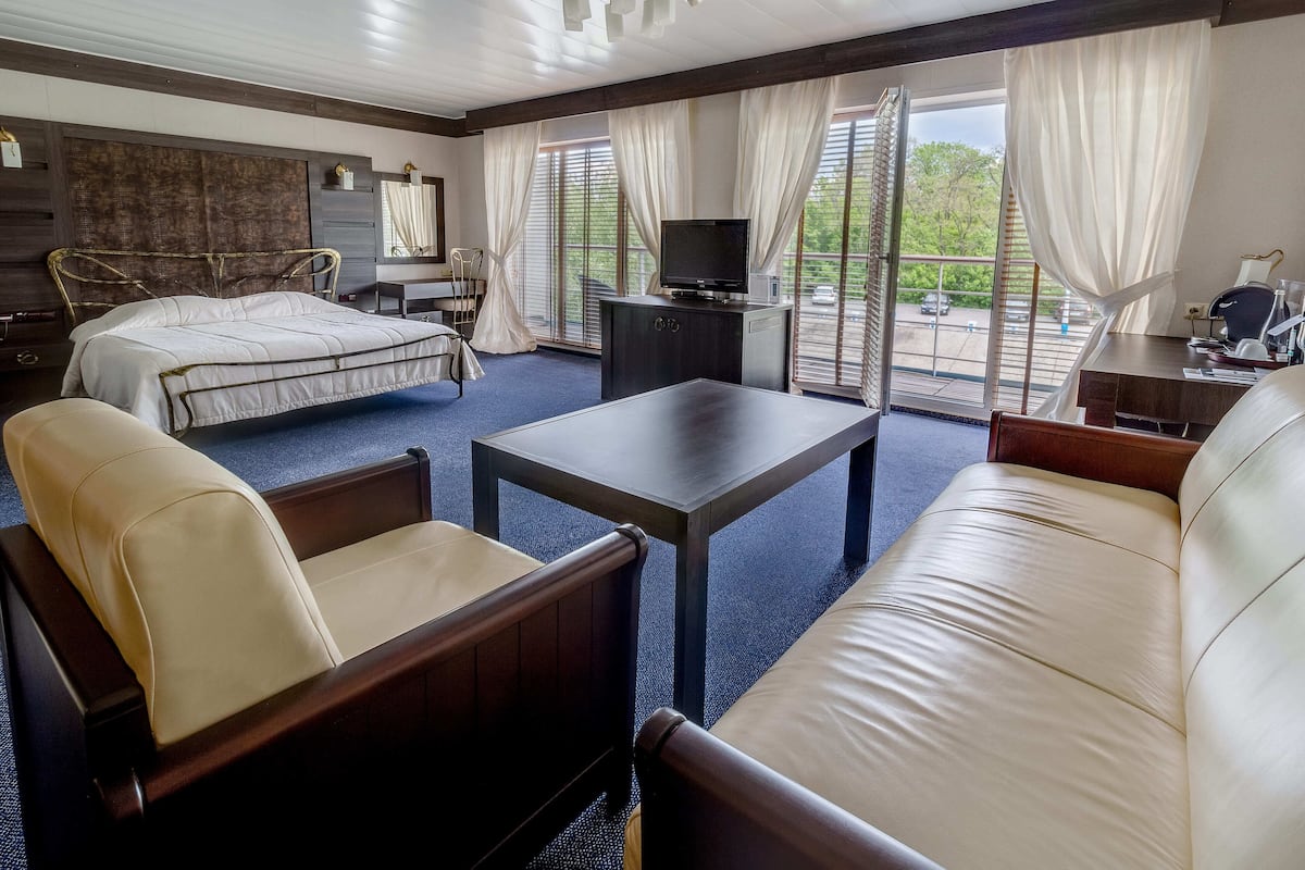 Une chambre d’hôtel comprenant un lit, un canapé, une table basse, une télévision et un bureau avec une chaise.