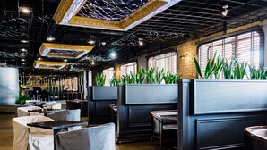 A restaurant with booth seating, a brick wall, and large windows. - Hotel Bakkara (Kyiv)