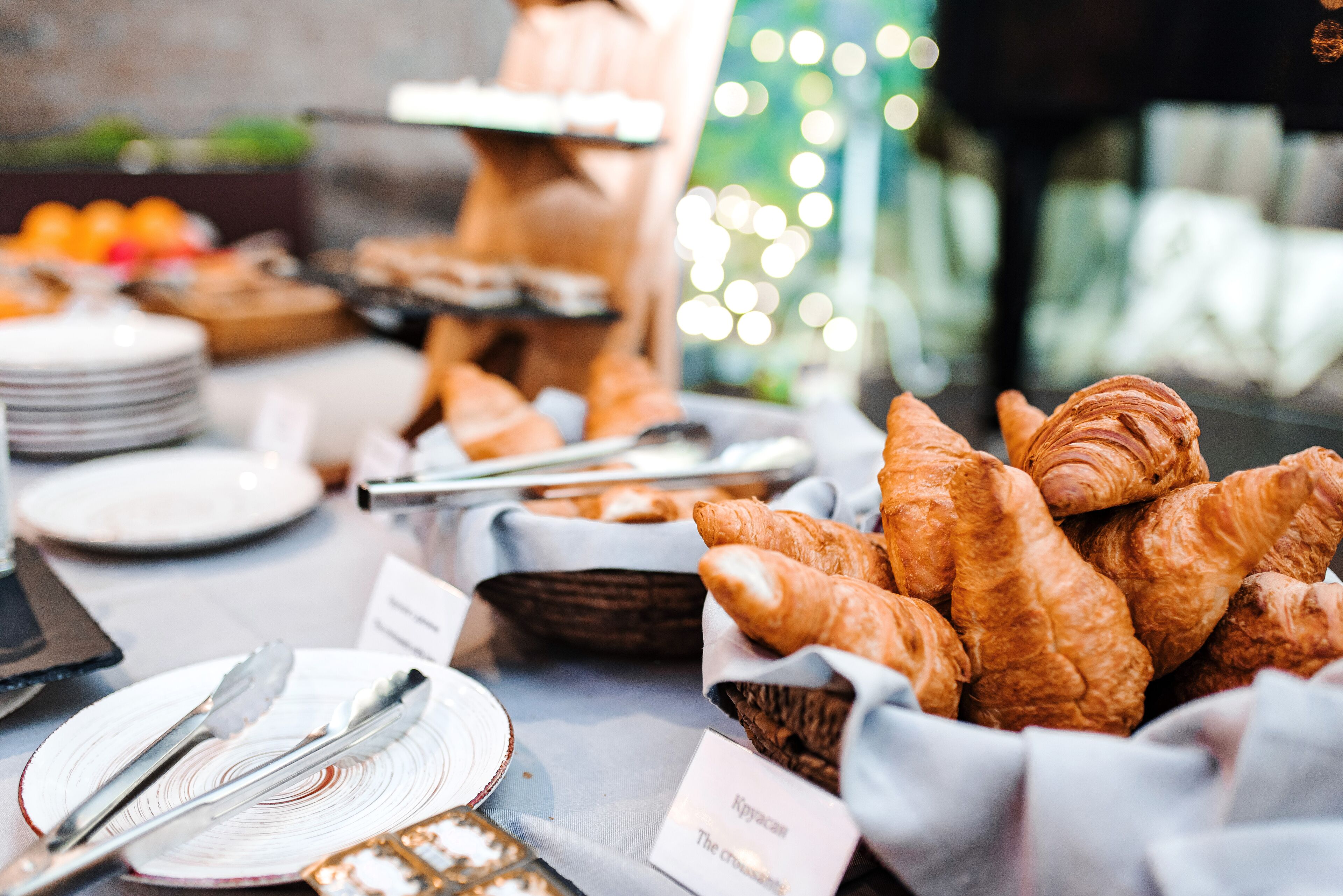 A buffet table with various food items, including croissants and a sign labeled "Kypca."