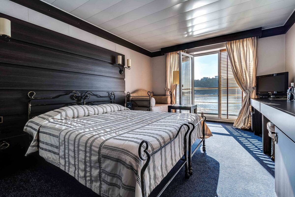 Une chambre d’hôtel avec un lit, un bureau, une télévision et une vue sur l’eau.