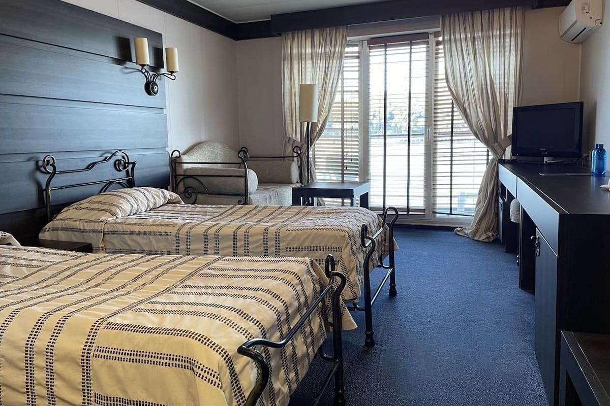 Une chambre d’hôtel avec deux lits, un bureau, une chaise et un téléviseur.