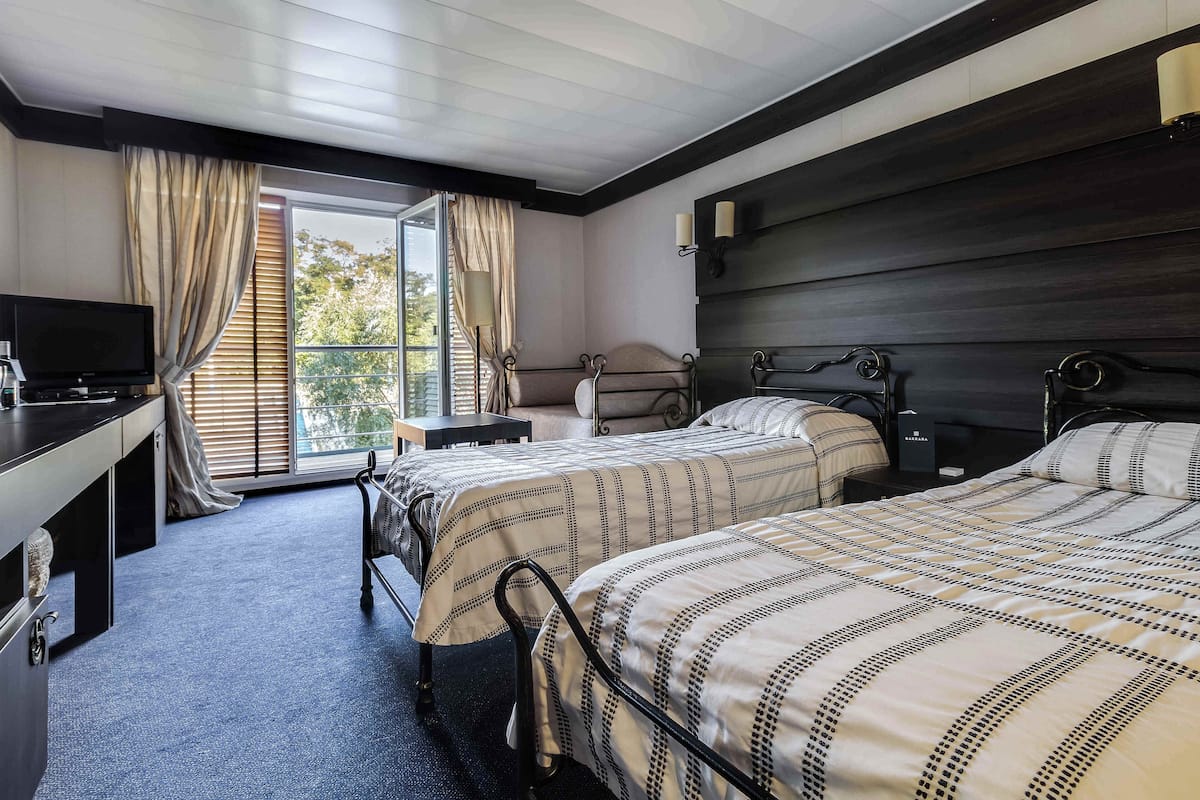 Une chambre d’hôtel avec deux lits, un bureau, une chaise et un téléviseur.