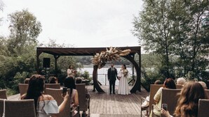 A wedding ceremony on a wooden deck with wicker chairs, overlooking a body of water. - Hotel Bakkara (Kyiv)