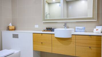 A bathroom with a white sink, wooden cabinets, a mirror, and a toilet.