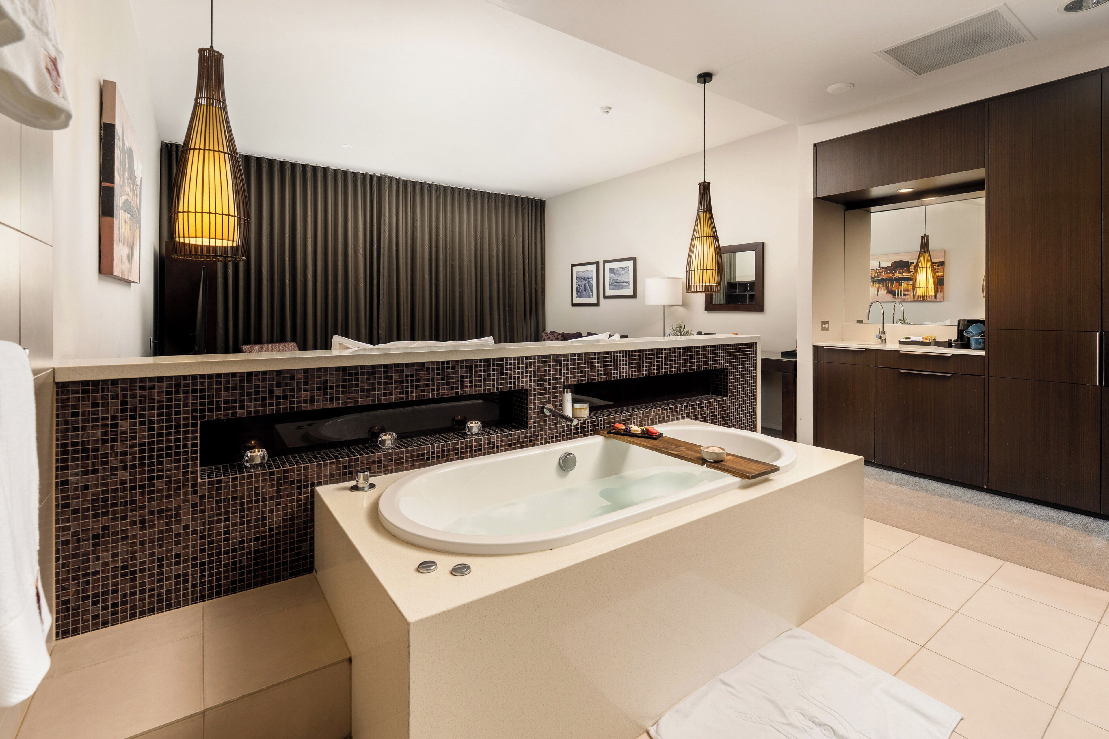 Une salle de bain moderne avec une baignoire îlot, un meuble-lavabo double avec un grand miroir et des luminaires suspendus.