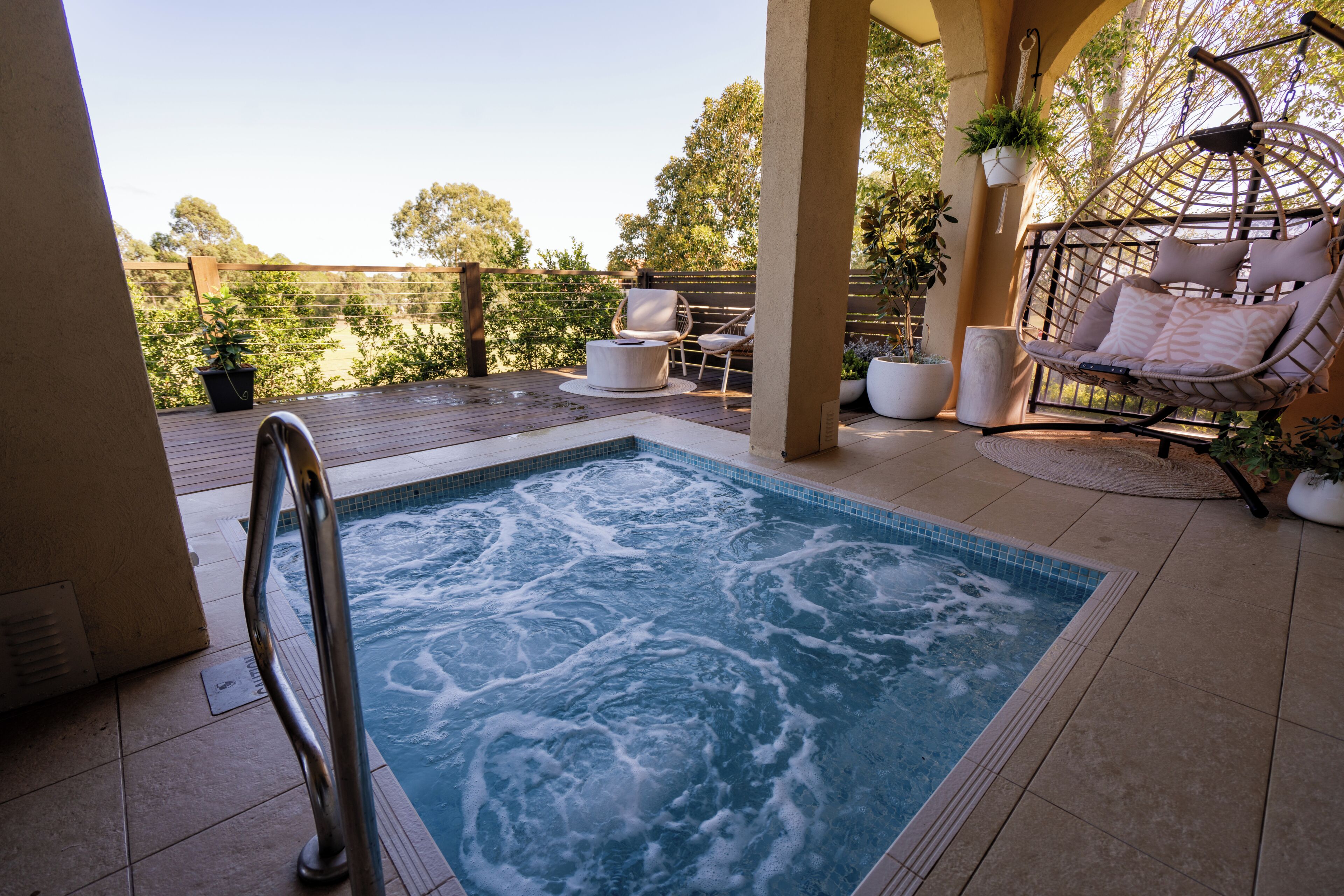 A hot tub with a view of a garden and a wooden deck.