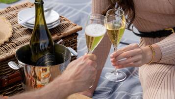 A picnic setup with a bottle of wine, glasses, and a fruit platter on a blanket.