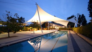 A swimming pool with a modern architectural structure in the background. - Chateau Elan At The Vintage (Pokolbin)