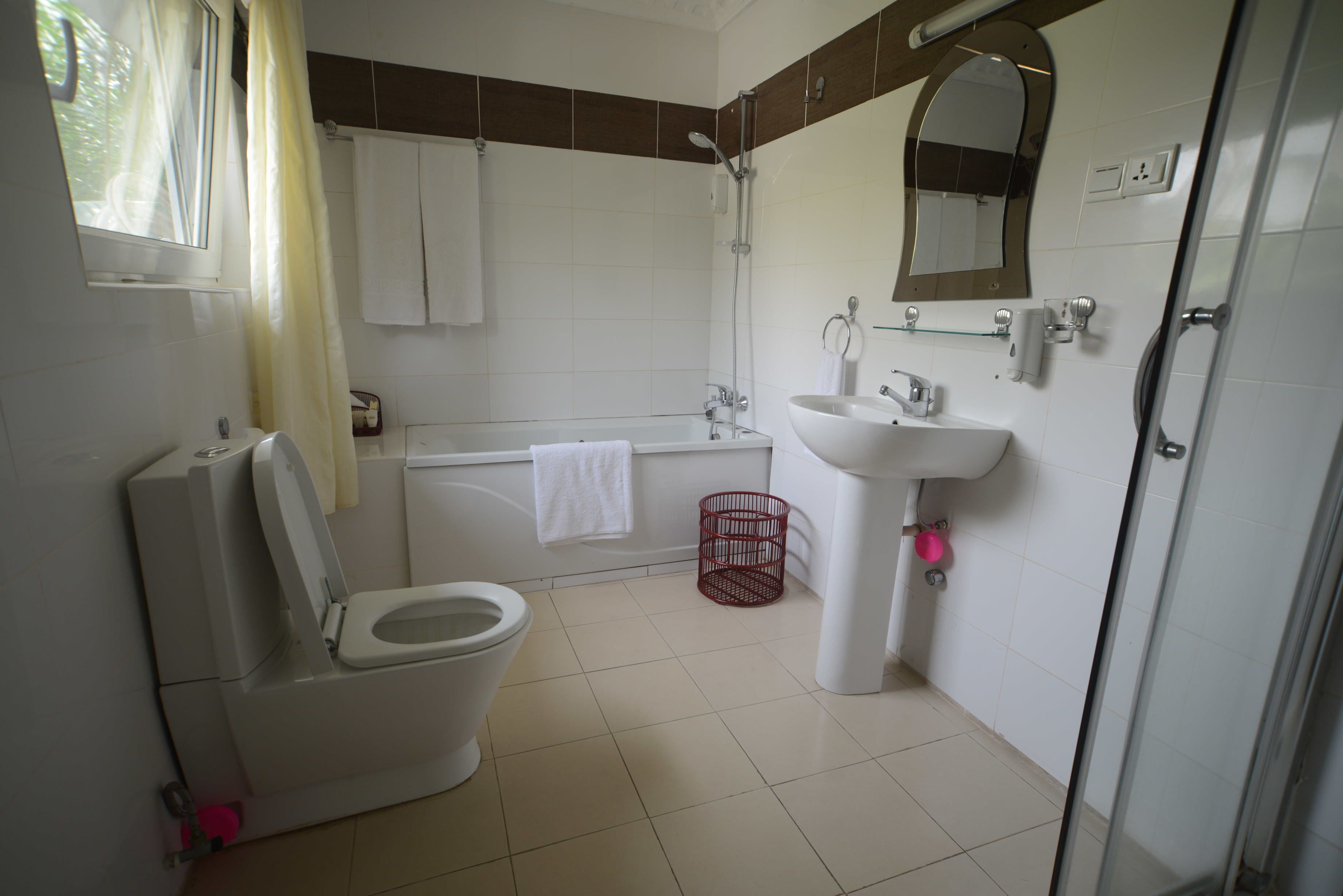 Une salle de bain comprenant des toilettes, une baignoire, un lavabo et une douche.