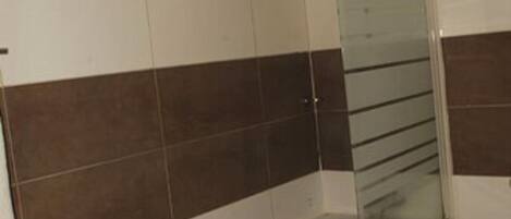 Un baño con bañera, cabina de ducha de vidrio y un inodoro blanco.