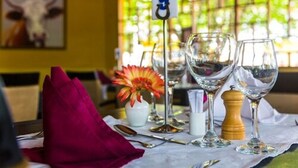 A table set with wine glasses, a flower vase, and a number sign. - Airside Hotel (Accra)