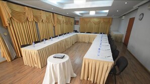 A conference room with a long table, round tables, and chairs. - Airside Hotel (Accra)