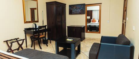 Una sala de estar con un sofá, una mesa de comedor con sillas, un aparador y una televisión.