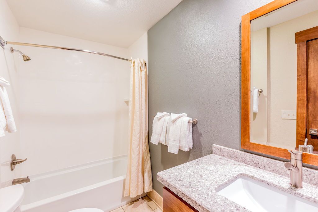 A bathroom with a bathtub, a sink with a mirror, and towels on the wall.