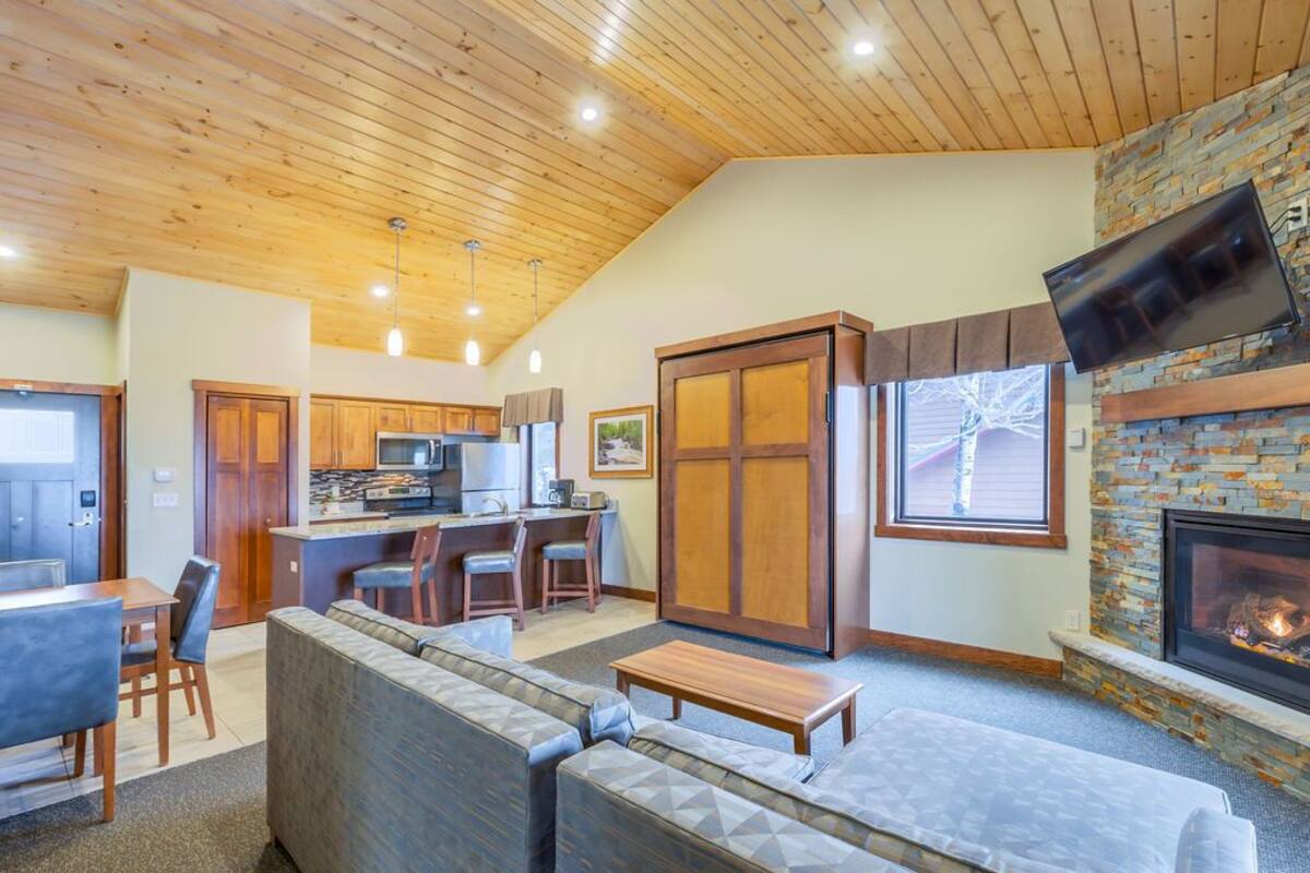 A spacious living area with a stone fireplace, a dining area, and a kitchen.