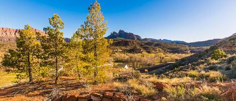 A stone wall in a natural landscape with trees and distant mountains.