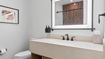 Une salle de bain moderne avec un double lavabo, des toilettes et un tableau encadré au mur.