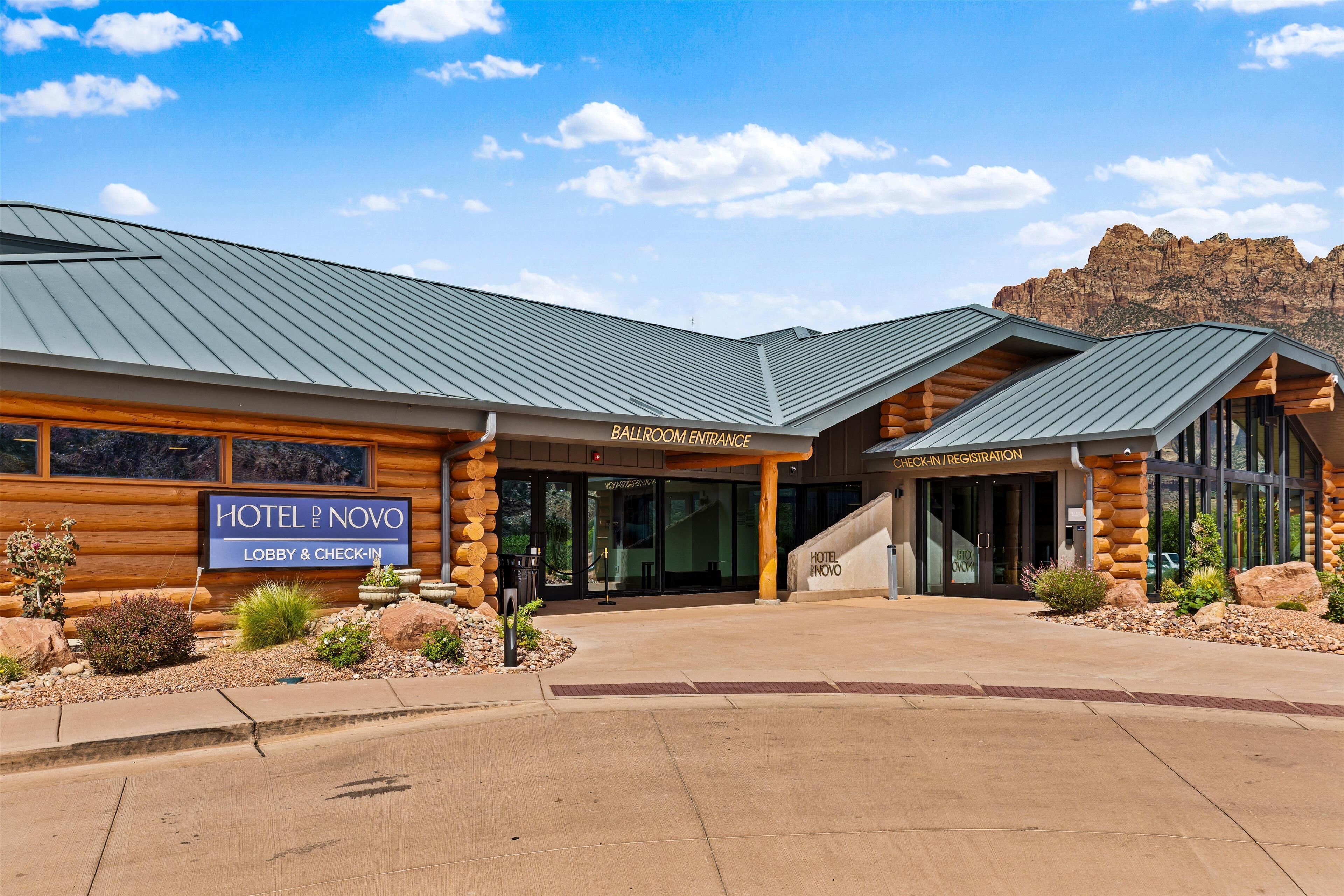 A hotel entrance with a sign for lobby and check-in, a check-in/registration area, and a view of the surrounding landscape.