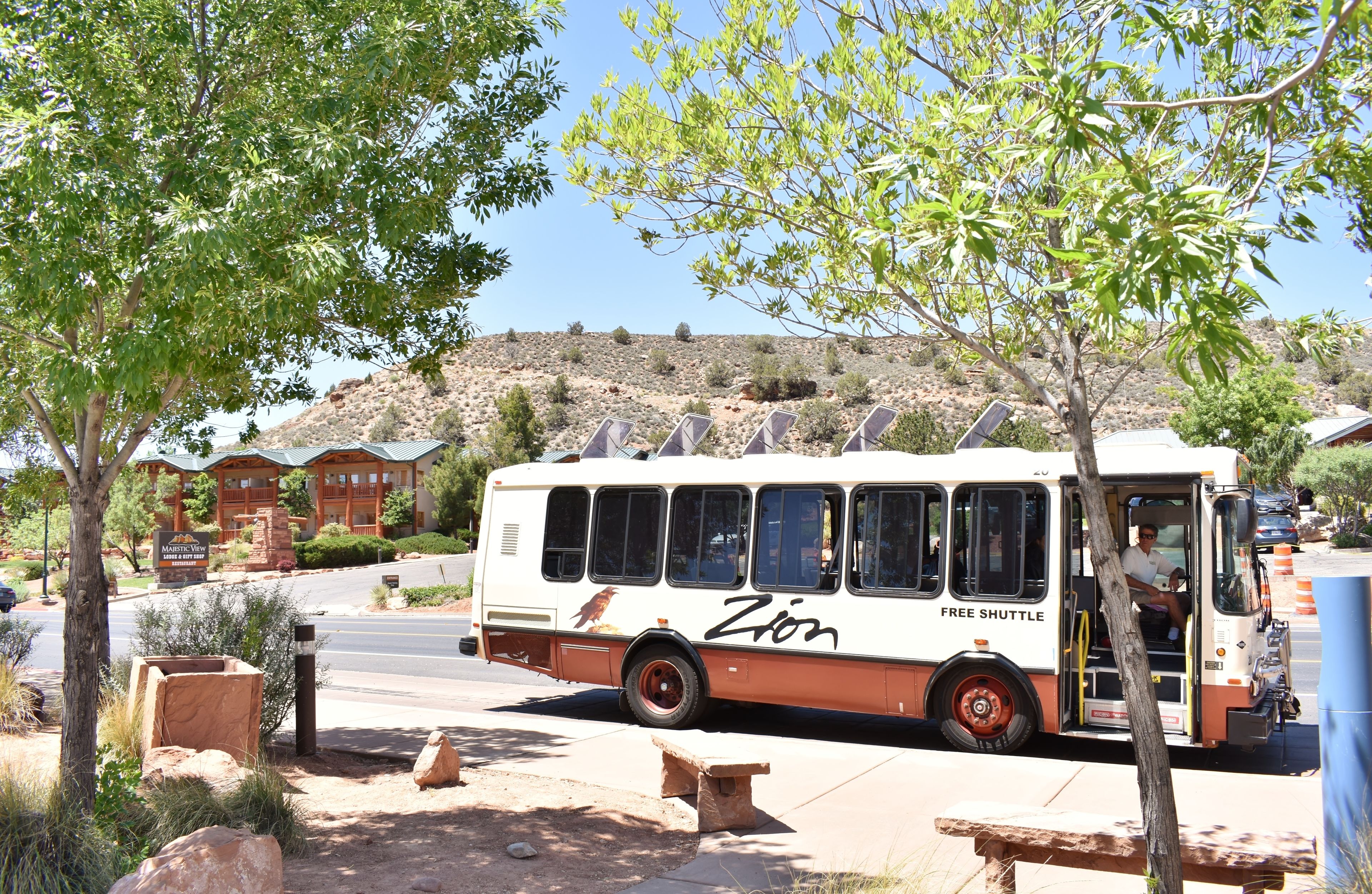 A bus with 'Zion' and 'Free Shuttle' written on it parked near a building with a sign that reads 'Master View'.