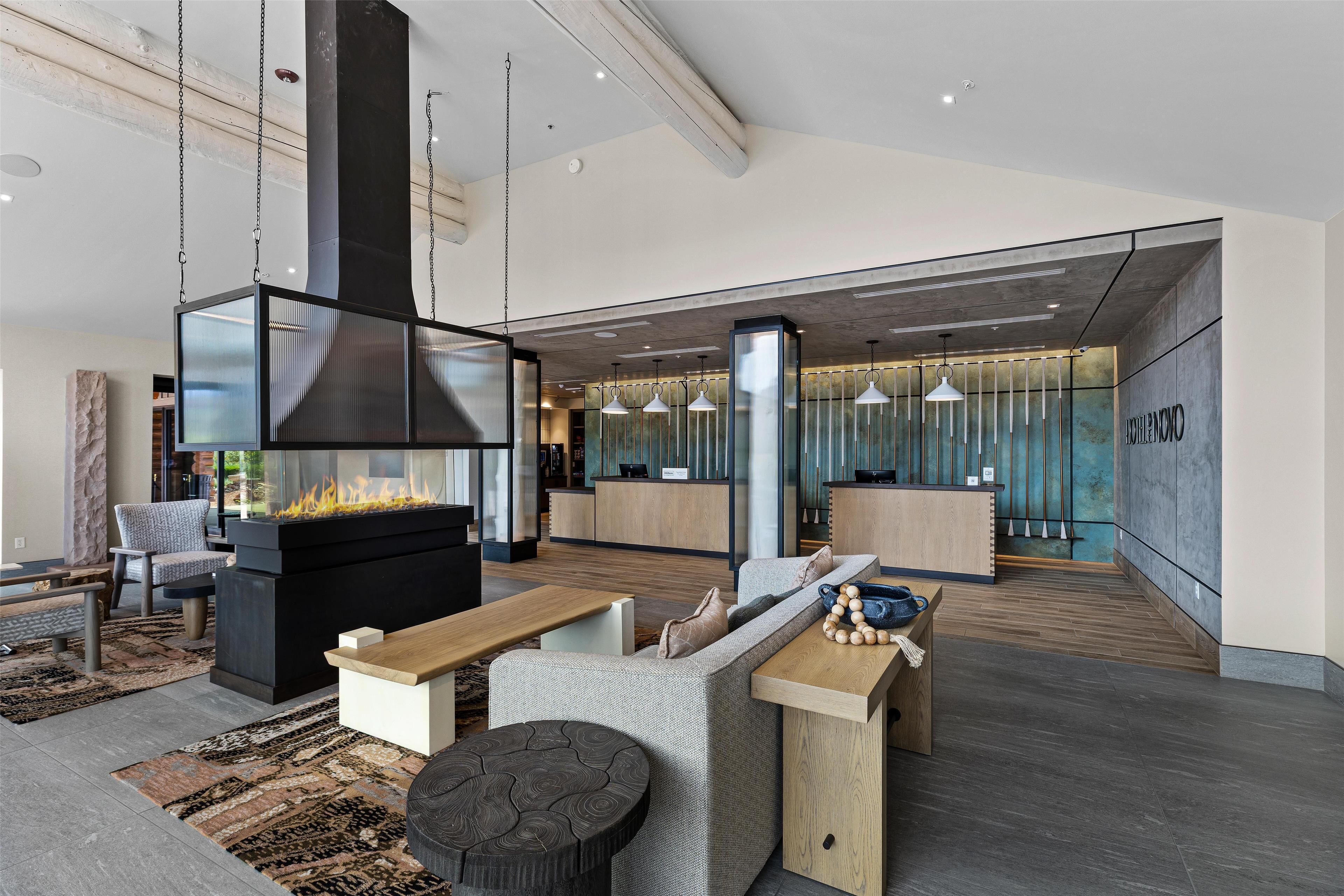 A modern living area with a fireplace, seating, and a kitchen area.