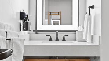 A modern bathroom with a wooden vanity, a large mirror, and a white sink.