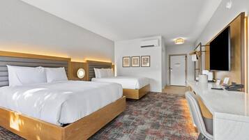 Une chambre d’hôtel avec deux lits, un bureau, un miroir et une moquette à motifs.