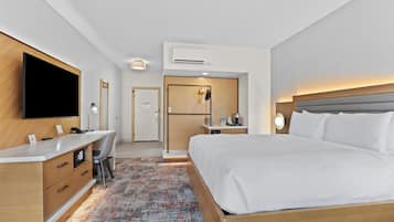 Een hotelkamer met een bed, bureau, stoel, televisie en een kleine kitchenette.