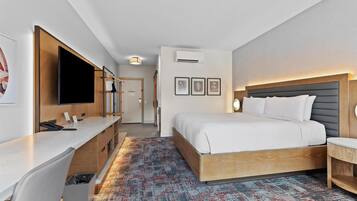 A hotel room with a bed, desk, and a television.