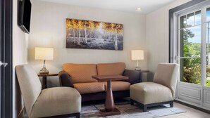 A modern living room with a sofa, two armchairs, a coffee table, and a painting on the wall. - Best Western Plus Mont-Laurier (Mont-Laurier)